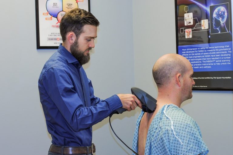 A doctor performing a neurological scan on a patient's back at Integral Wellness Co. in Johnson City