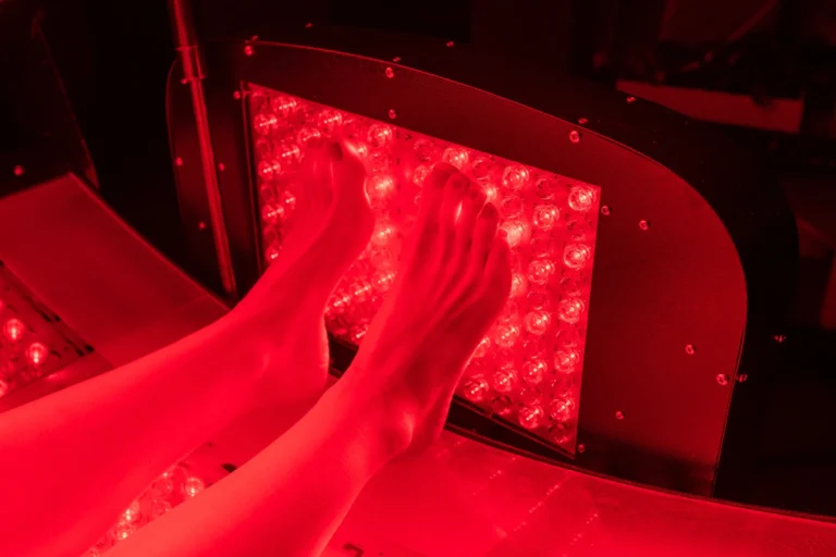 Feet resting against a red light therapy panel